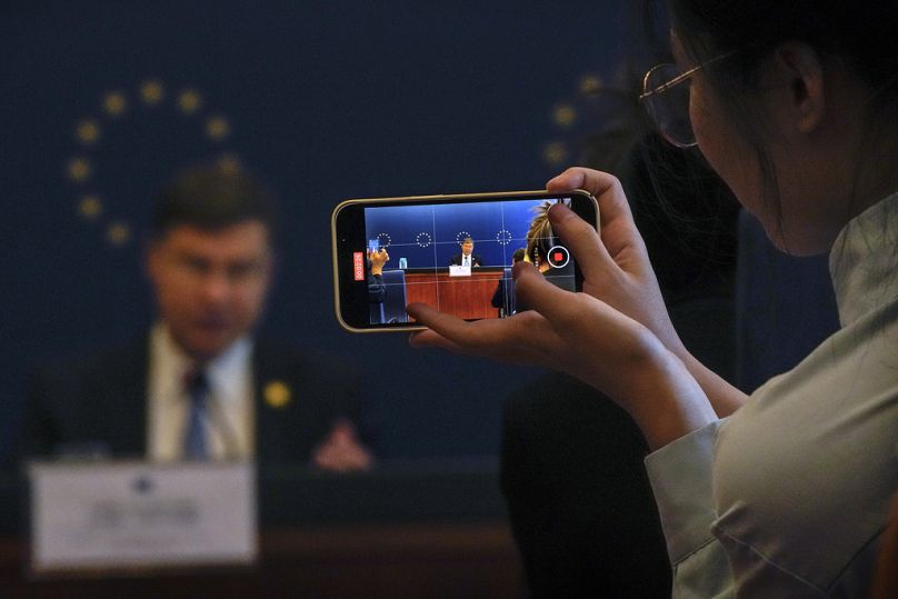 Dziennikarz używa smartfona do filmowania europejskiego komisarza ds. gospodarki i handlu Valdisa Dombrovskisa przemawiającego na konferencji prasowej w Pekinie, wrzesień 2023 r.