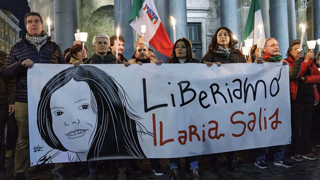 Demonstrators hold up a banner with writing (Italian)