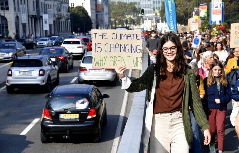 Dziewczyna trzyma znak informujący o nadjeżdżających pojazdach, uczestnicząc w marszu i demonstracji klimatycznej w Brukseli, październik 2021 r.