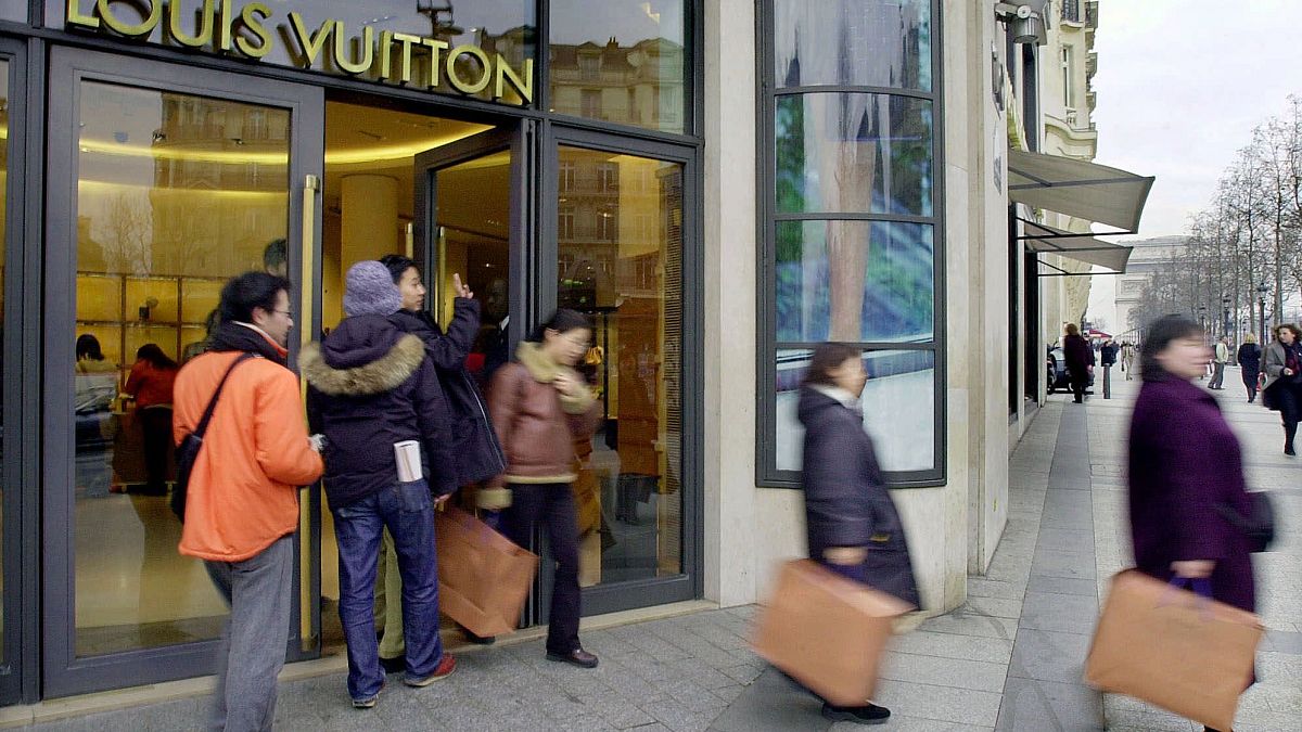 Shoppers leave the Champs Elysees Louis Vuitton shop in Paris