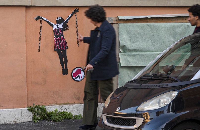 Przechodnie patrzą na malowidło ścienne przedstawiające włoską działaczkę antyfaszystowską Ilarię Salis w akcie zrywania łańcuchów w pobliżu Ambasady Węgier w Rzymie, środa, 31 stycznia