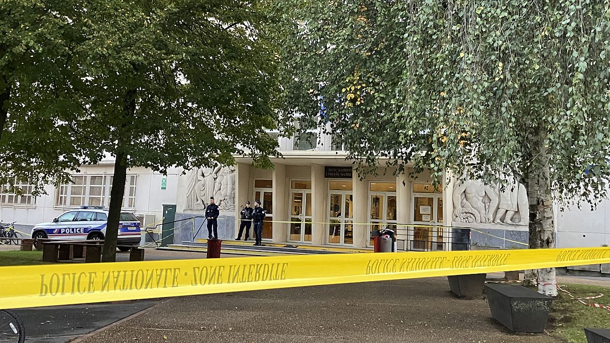 Police officers stand guard outside the secondary school where a man stabbed a teacher, Saturday, October 14, 2023 in Arras, northern France.