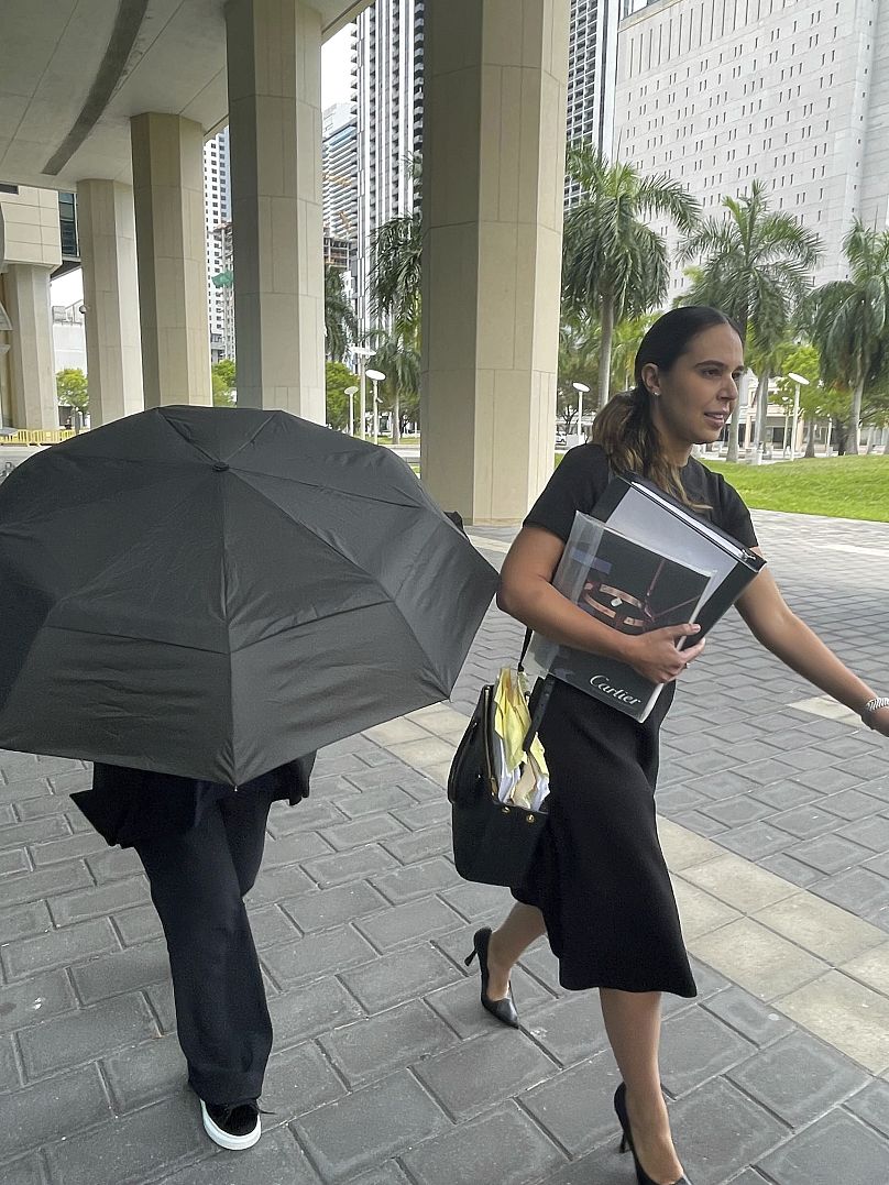 Projektantka torebek gwiazd, Nancy Gonzalez, ukrywa się pod parasolem, spacerując ze swoją prawniczką Andreą Lopez przed budynkiem sądu federalnego, poniedziałek, 22 kwietnia 2024 r., w Miami.