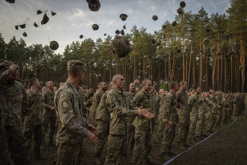 Nowo werbowani żołnierze wykrzykują hasła, świętując zakończenie szkolenia w bazie wojskowej niedaleko Kijowa na Ukrainie, poniedziałek, 25 września 2023 r.