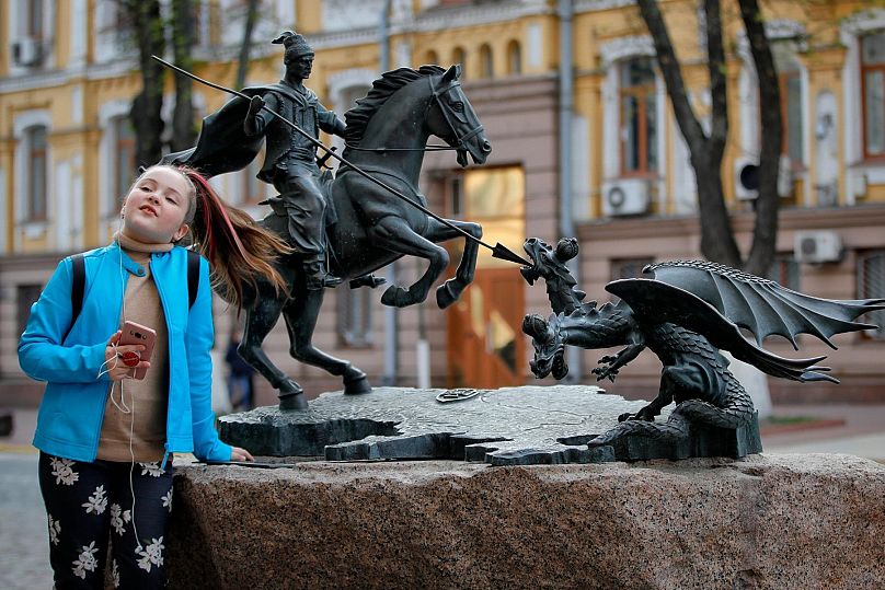 PLIK – Dziecko pozuje w pobliżu przedstawienia św. Jerzego zabijającego smoka w Kijowie na Ukrainie