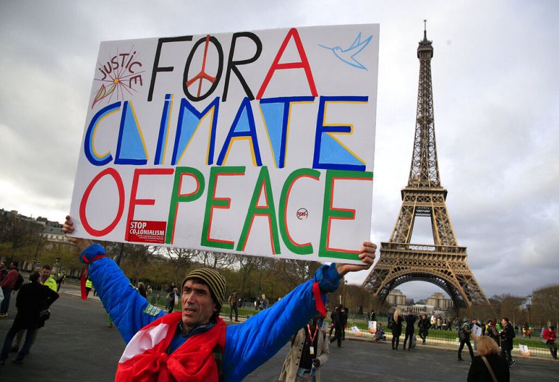 Aktywista trzyma plakat podczas demonstracji w pobliżu Wieży Eiffla podczas COP21 w Paryżu, grudzień 2015