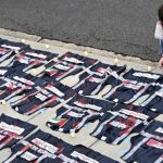 A demonstrator lays candles on the ground next to press vest covered in red paint during a pro-Palestinian protest over the Israel-Hamas war on Saturday April 27, 2024,
