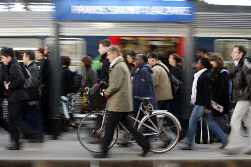 Osoba dojeżdżająca do pracy spaceruje z rowerem obok pociągu w Saint Lazare w Paryżu, marzec 2009