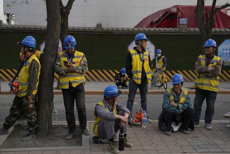Pracownicy czekają na przejazd przed placem budowy w Pekinie, kwiecień 2024 r