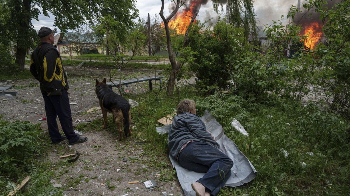 A police officer runs in front on burning house destroyed by a Russian airstrike in Vovchansk, Ukraine