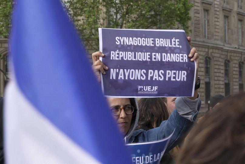 Demonstranci trzymają plakat z napisem „Spalono synagogę, Republika w niebezpieczeństwie, nie bójmy się” podczas zgromadzenia w Paryżu, 17 maja 2024 r.