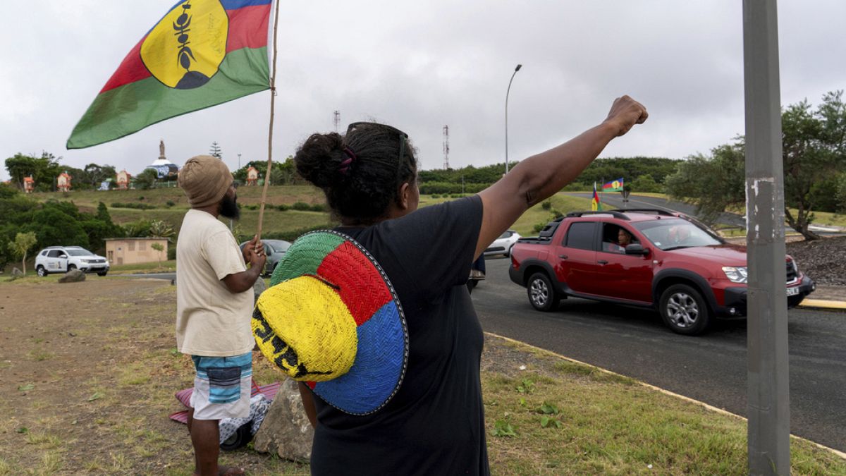 A woman waves a Kanak and Socialist National Liberation Front (FLNKS) flag in Noumea, New Caledonia, Wednesday May 15, 2024.