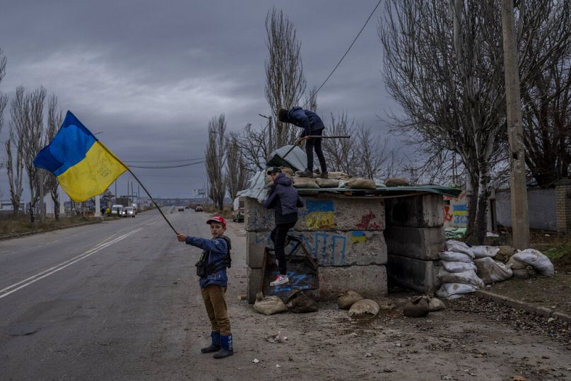 Ukraińskie dzieci bawią się na opuszczonym punkcie kontrolnym w Chersoniu, listopad 2022 r