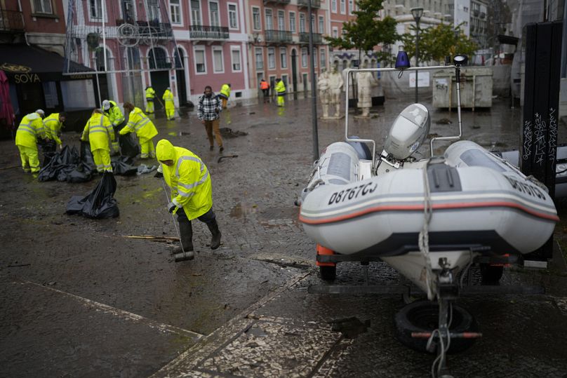 Pracownicy miejscy sprzątają zalaną w nocy ulicę w Alges pod Lizboną, grudzień 2022 r