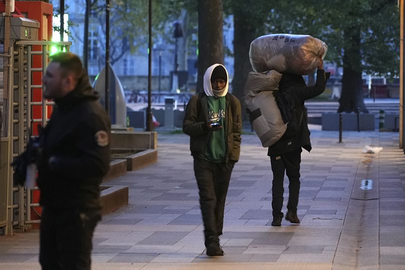 Migranci opuszczają prowizoryczny obóz po eksmisji przez funkcjonariuszy policji, wtorek, 23 kwietnia 2024 r. w Paryżu.