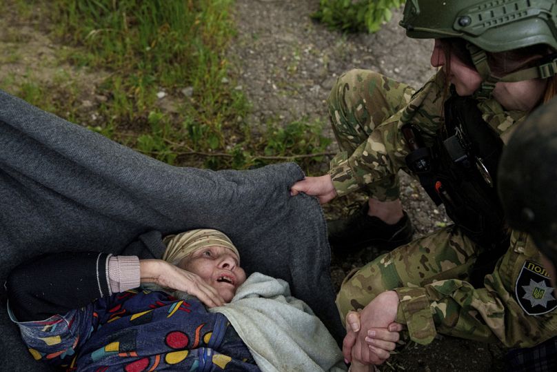Policjant rozmawia ze starszą kobietą po rosyjskim nalocie podczas ewakuacji w Wowczańsku na Ukrainie