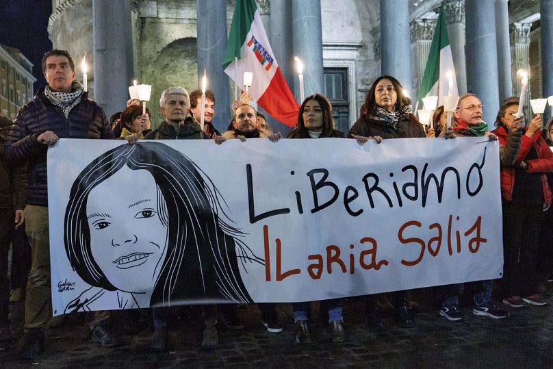 Demonstranci trzymają transparent z napisem czytającym w języku włoskim 