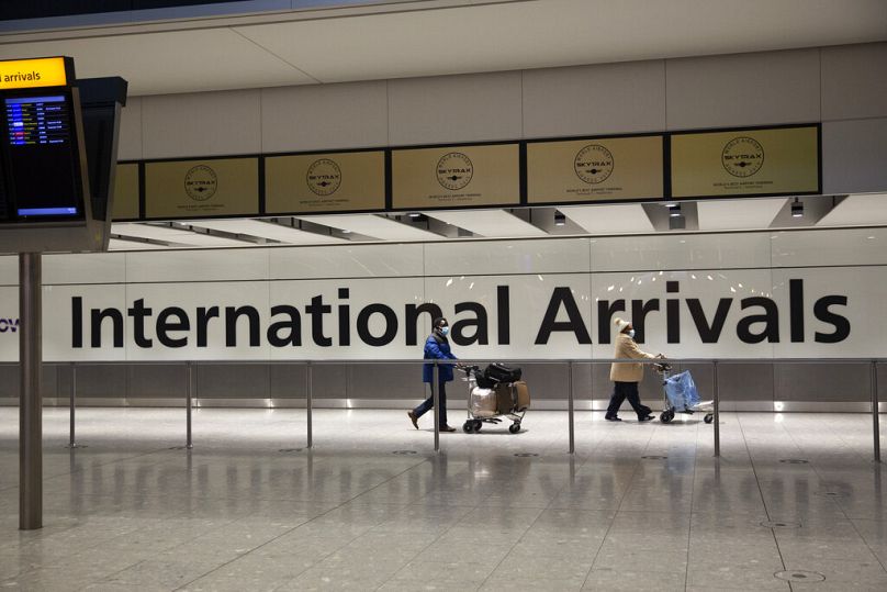Przylatujący pasażerowie mijają znak w strefie przylotów na lotnisku Heathrow