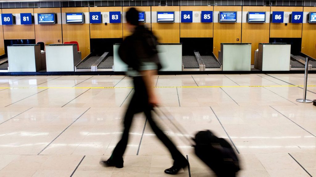 A passenger walks past vacant check-in desks at Paris Orly airport, France, during a strike by French air traffic controllers