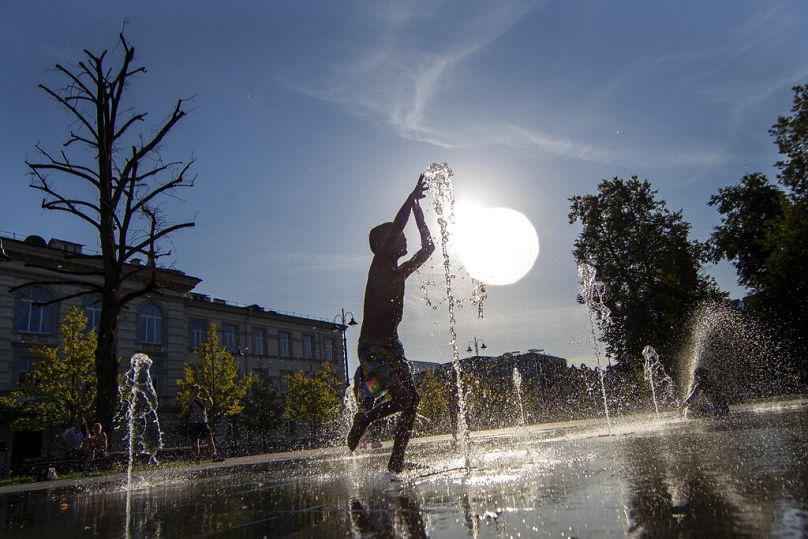 Chłopiec chłodzi się w publicznej fontannie w Wilnie na Litwie.