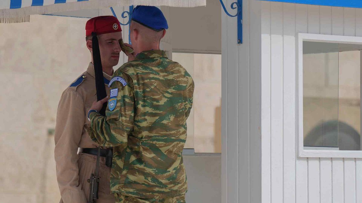 An army officer wipes the face of a member of the presidential guard, at the tomb of the Unknown Soldier, central Athens, on Thursday June 13, 2024.