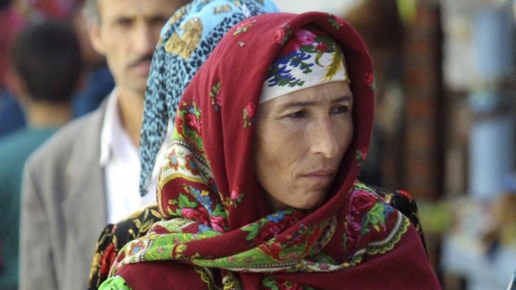 A woman in traditional colorful Tajik dress carries a bundle of bread at the Green Bazaar, in Dushanbe, 7 October 2001