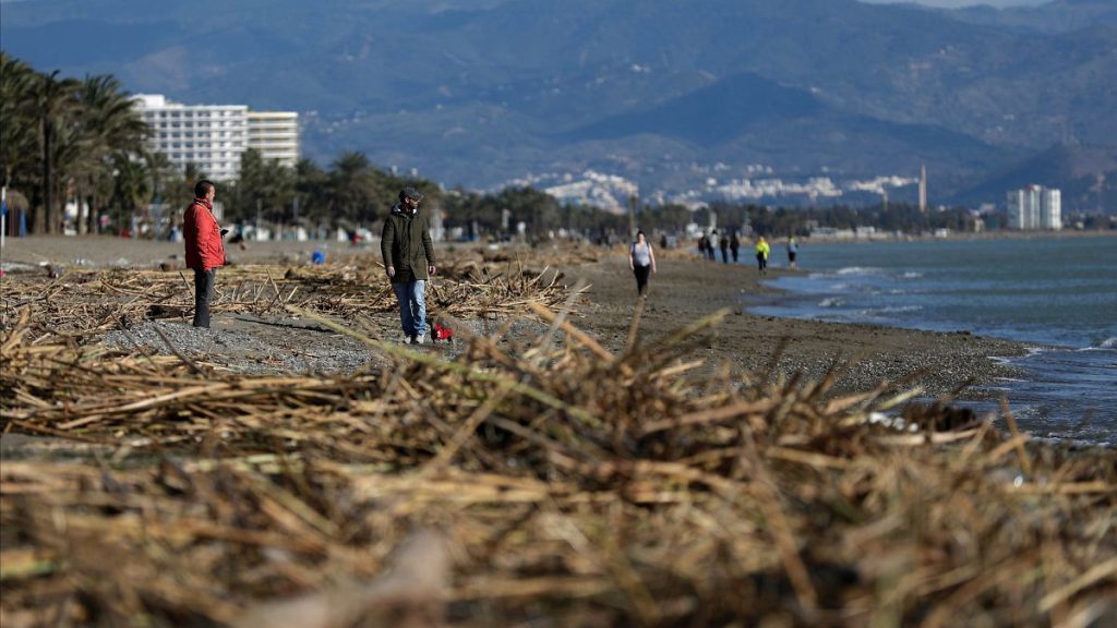 People walk along the beach after storm Gloria battered Spain