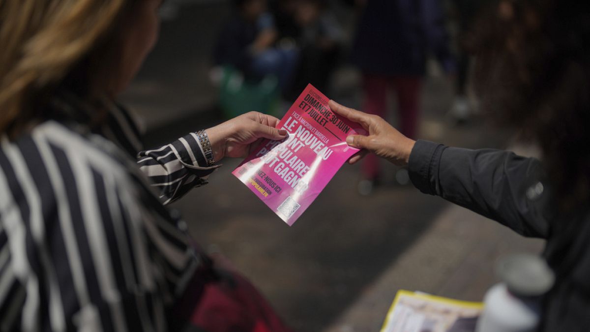 A campaign volunteer for the New Popular Front candidates hands out electoral leaflets for the upcoming parliamentary elections in Paris, Saturday June 22, 2024.