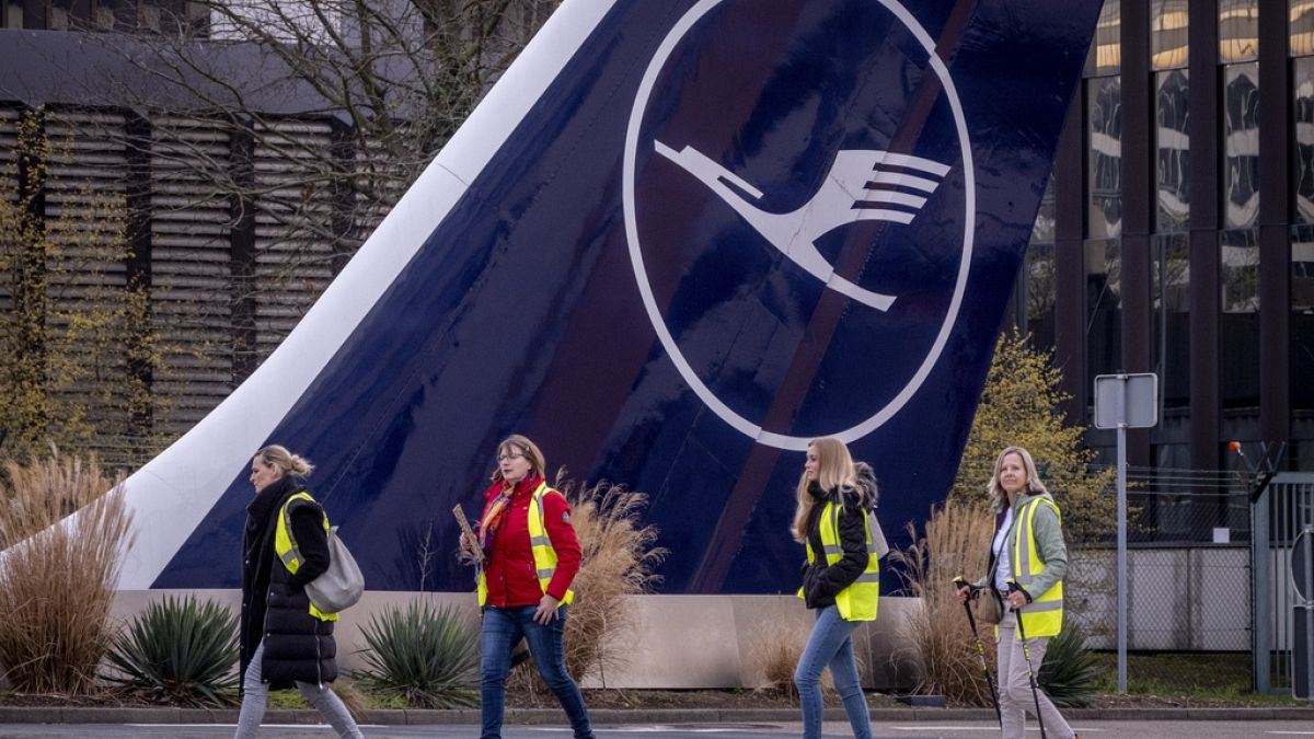 Striking Lufthansa flight attendants walk past a tail of an aircraft in Frankfurt, Germany, Tuesday, March 12, 2024.