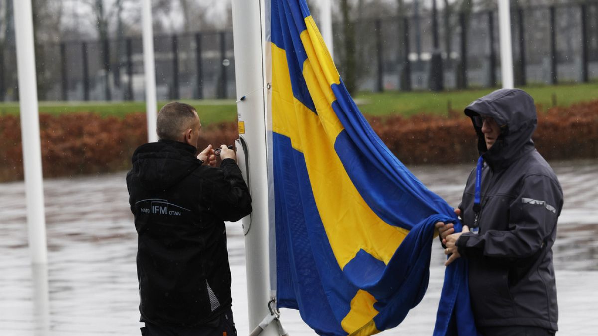 Members of protocol attach the Swedish flag as they prepare for a flag raising ceremony to mark the accession of Sweden at NATO headquarters in Brussels, Monday, March 11, 202