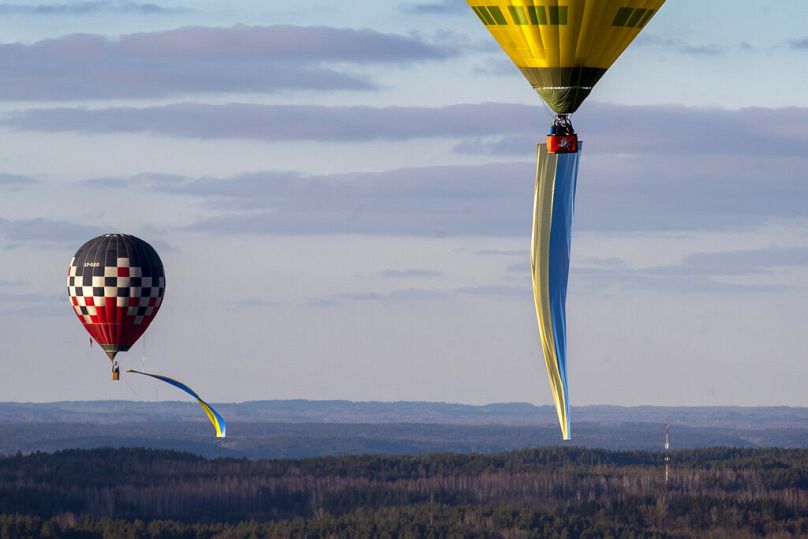 Balony na ogrzane powietrze ozdobione ukraińskimi flagami narodowymi unoszą się w powietrzu podczas protestu przeciwko rosyjskiej inwazji na Ukrainę w Wilnie, kwiecień 2022 r.