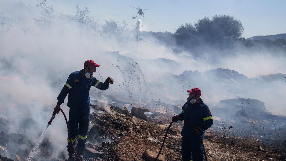 Firefighters try to extinguish the fire as a helicopter drops water in Koropi suburb in eastern Athens on 19 June, 2024.