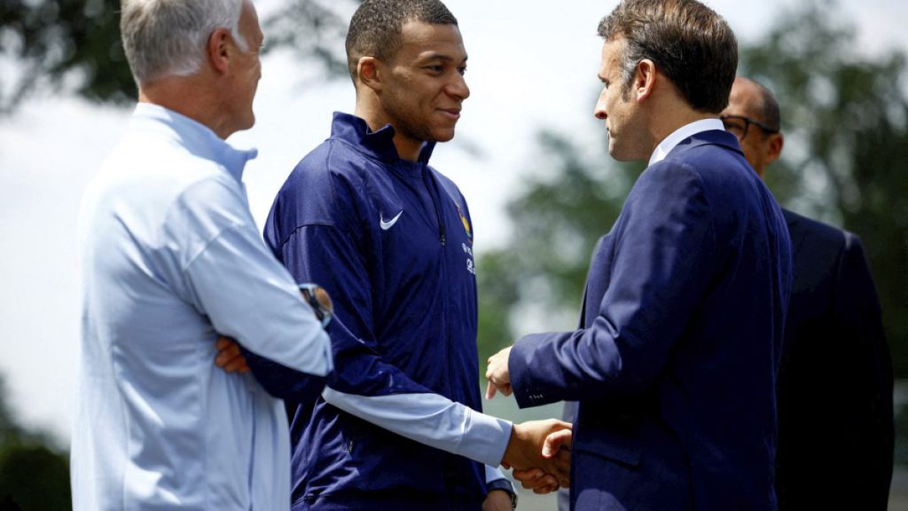 French President Emmanuel Macron, right, shakes hands with Kylian Mbappe next to head coach Didier Deschamps in Paris, June 3 2024