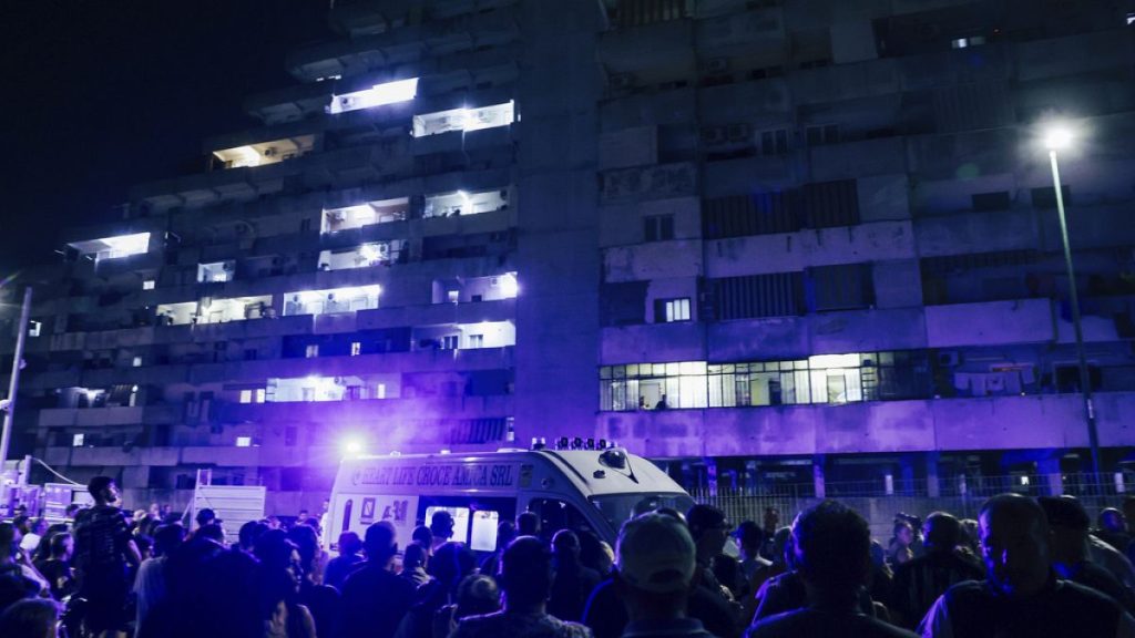 People gather in front of a building where a pedestrian walkway in a massive housing project collapsed in the southern Italian city of Naples, Tuesday, 23,2024.