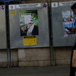People walk past campaign boards for the upcoming parliamentary elections in Paris, Saturday June 22