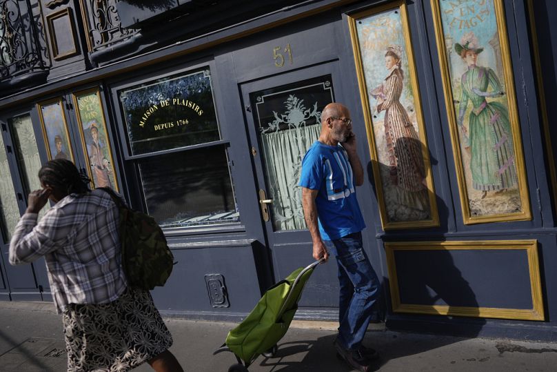 Ludzie przechodzą obok restauracji ozdobionej dziełami sztuki przed Letnimi Igrzyskami Olimpijskimi 2024 w Paryżu, lipiec 2024 r.