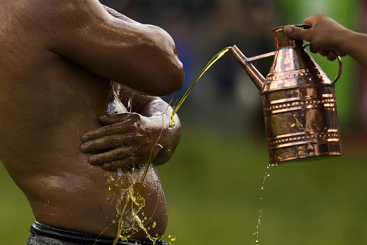 Zapaśnik oblewany jest olejem przez osobę polejącą go olejem podczas 663. dorocznych Mistrzostw Historycznych Kirkpinar Oil Wrestling w Edirne, w północno-zachodniej Turcji.