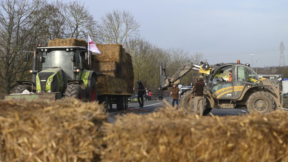 Farmers install hay bales on a highway near Paris