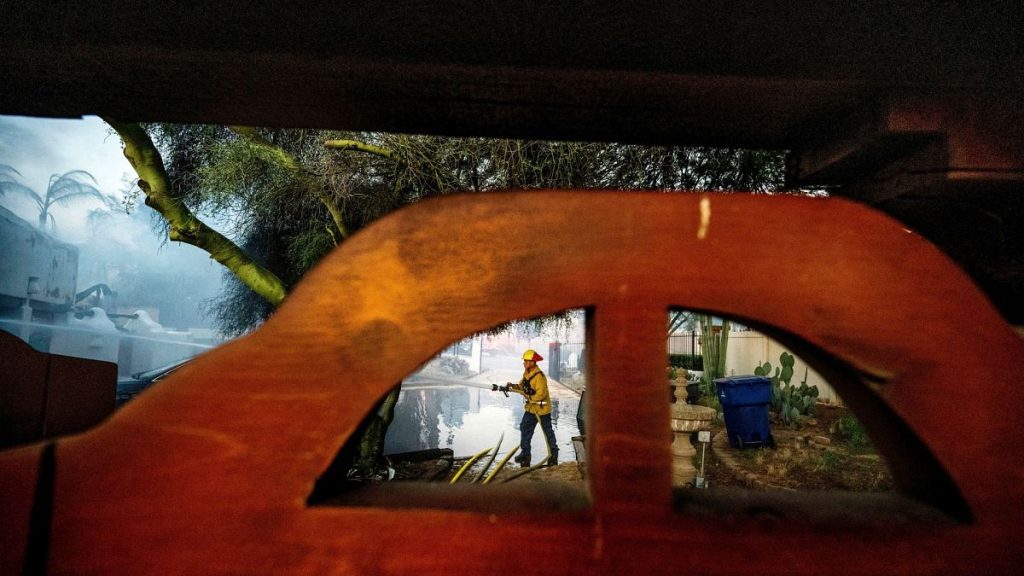 A firefighter hoses down the garage of a home that was destroyed by the Hawarden Fire in Riverside, California, on 21 July 2024.