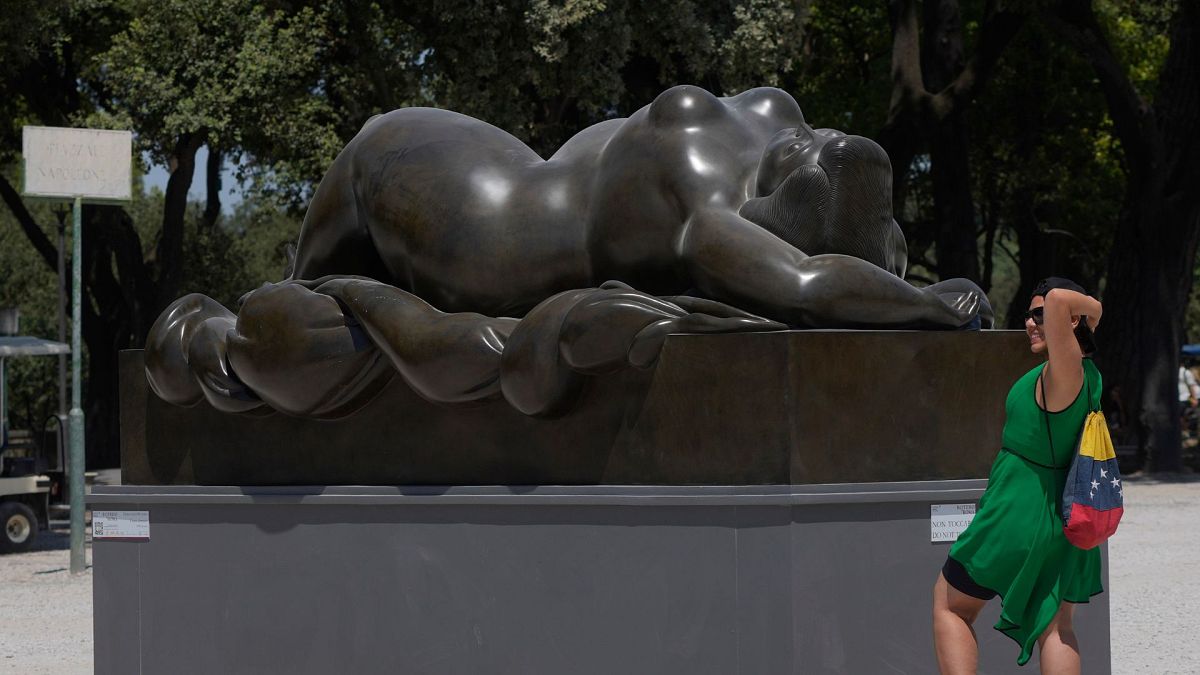 A woman poses for a picture near Fernando Botero