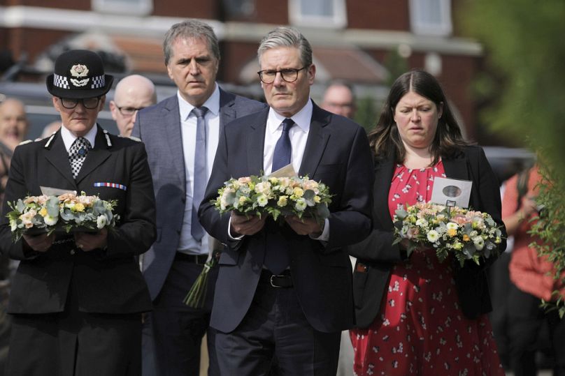 Brytyjski premier Keir Starmer (środek) niesie kwiaty w pobliżu miejsca zdarzenia na Hart Street, gdzie w ataku nożem zginęło troje dzieci, a ośmioro zostało rannych 