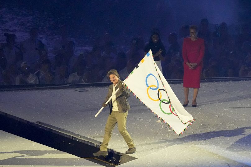 Tom Cruise trzyma flagę olimpijską podczas ceremonii zamknięcia Letnich Igrzysk Olimpijskich 2024 na Stade de France, w niedzielę 11 sierpnia 2024 r. w Saint-Denis we Francji.