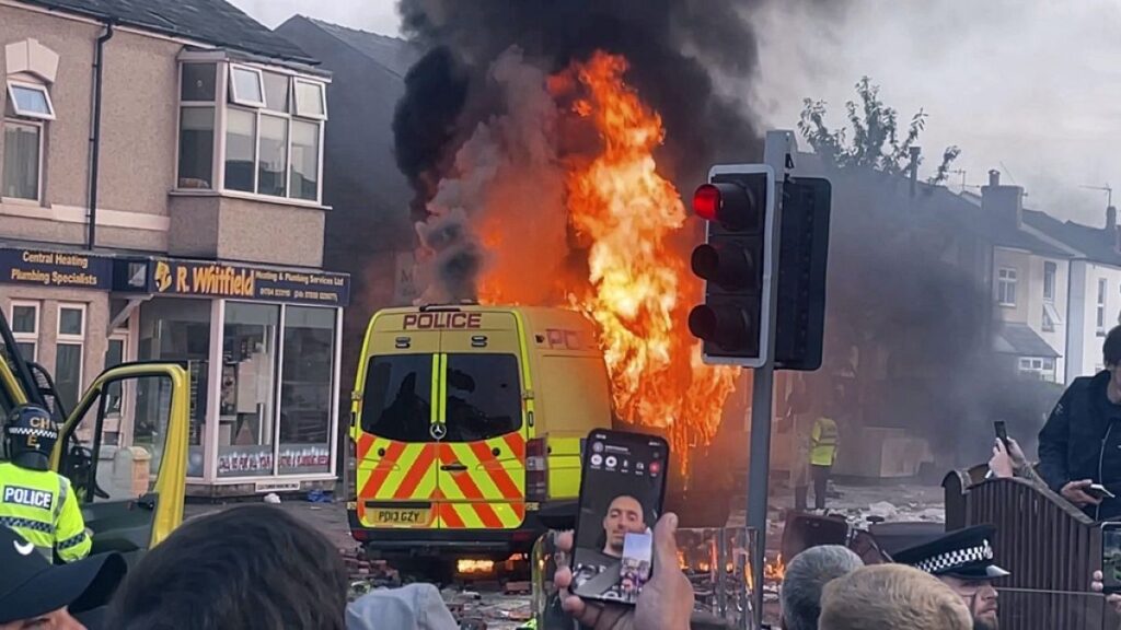 A police van buns as and unruly crowd clashed with police, Tuesday, July 30, 2024, in Southport, northwest England