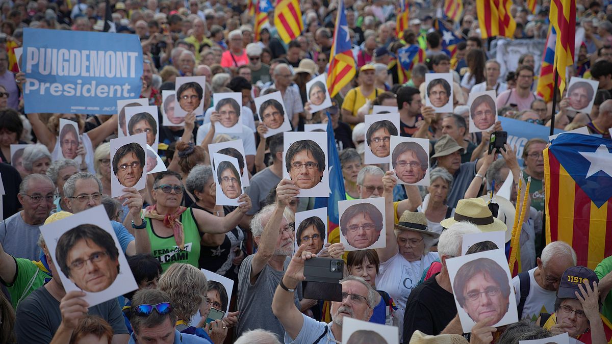 Supporters of Catalan independence leader Carles Puigdemont hold his portrait as they wait for his arrival near the Catalan parliament in Barcelona, 8 August 2024