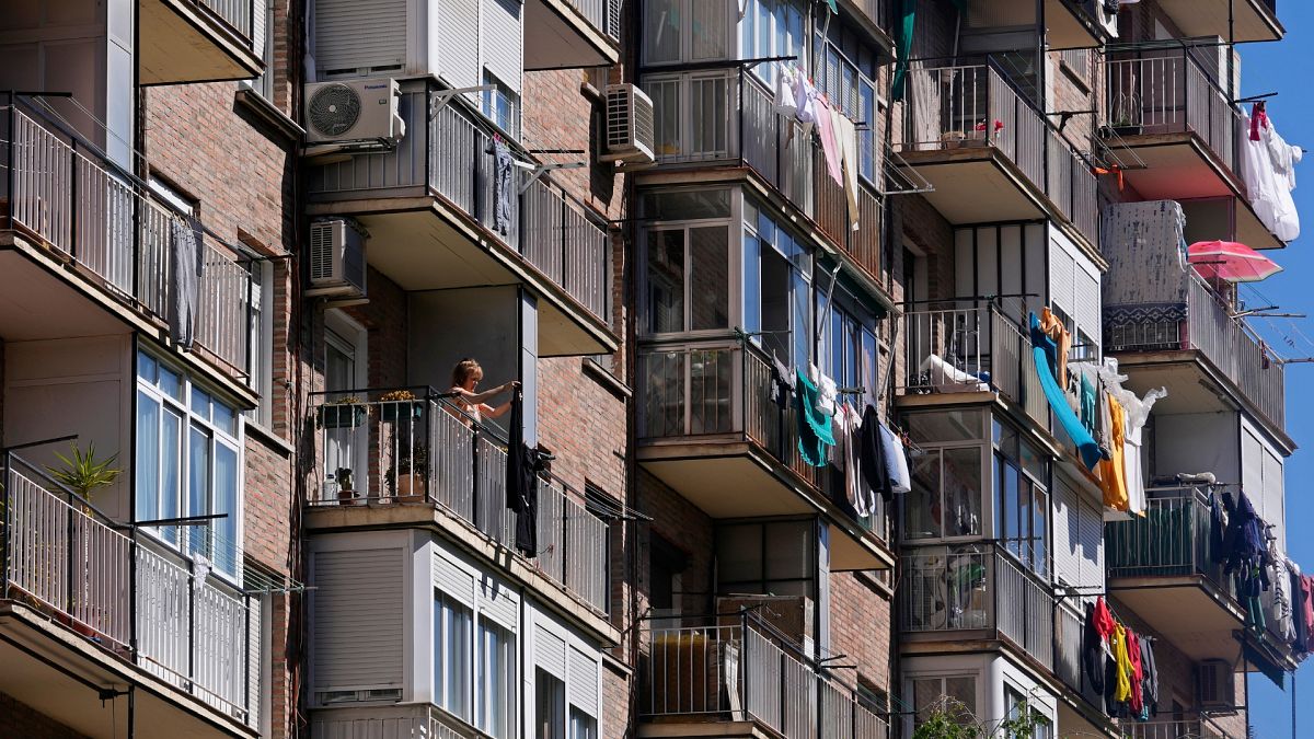 A woman hangs clothes to dry on her balcony of a housing block in Madrid, Spain.