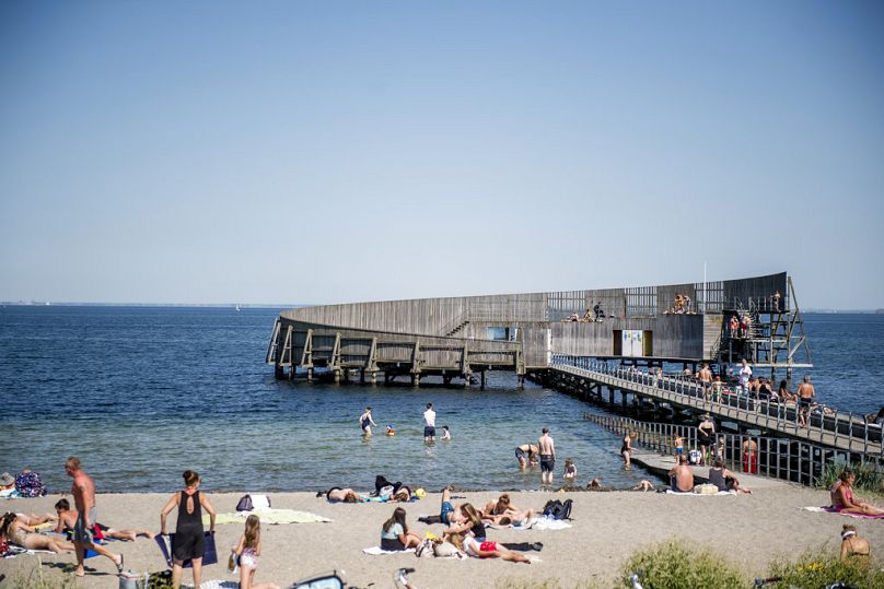 Ludzie kąpią się w morzu i siedzą na plaży w nadmorskim kurorcie Kastrup w Kopenhadze, Dania, piątek 1 czerwca 2018 r. 