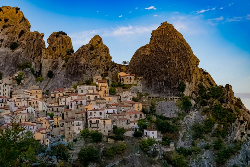 Wieś Castelmezzano przylega do gigantycznych odłamków szarych skał wznoszących się ponad linią drzew. 