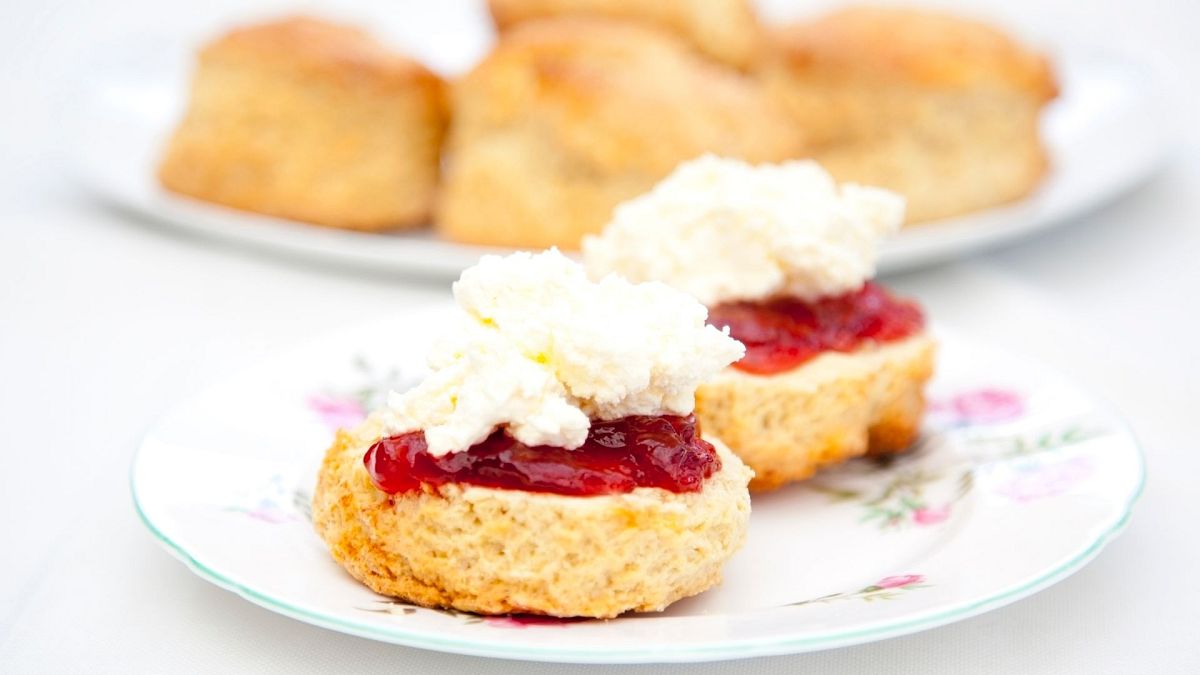 A scone with jam and cream on top, showing the