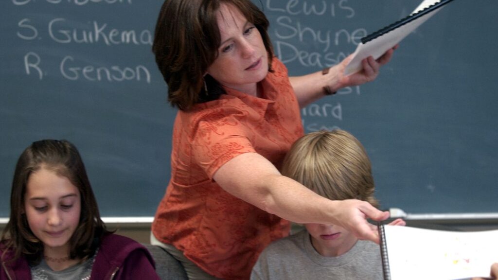 Counselor Kelley Peel, center, hands out copies of the students book they wrote and illustrated entitled "Kid