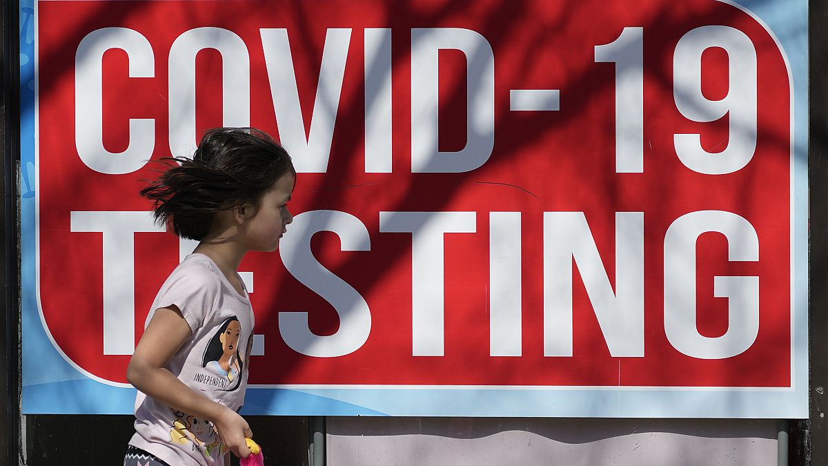 A COVID-19 test sign is displayed at a store as a child runs past in Chicago, Monday, March 11, 2024.